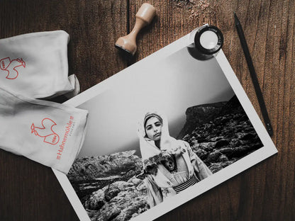 Black and White Photography Wall Art Greece | Girl wearing the traditional costume of Tilos island at a windy cliff Dodecanese Greece by George Tatakis - photo print on table