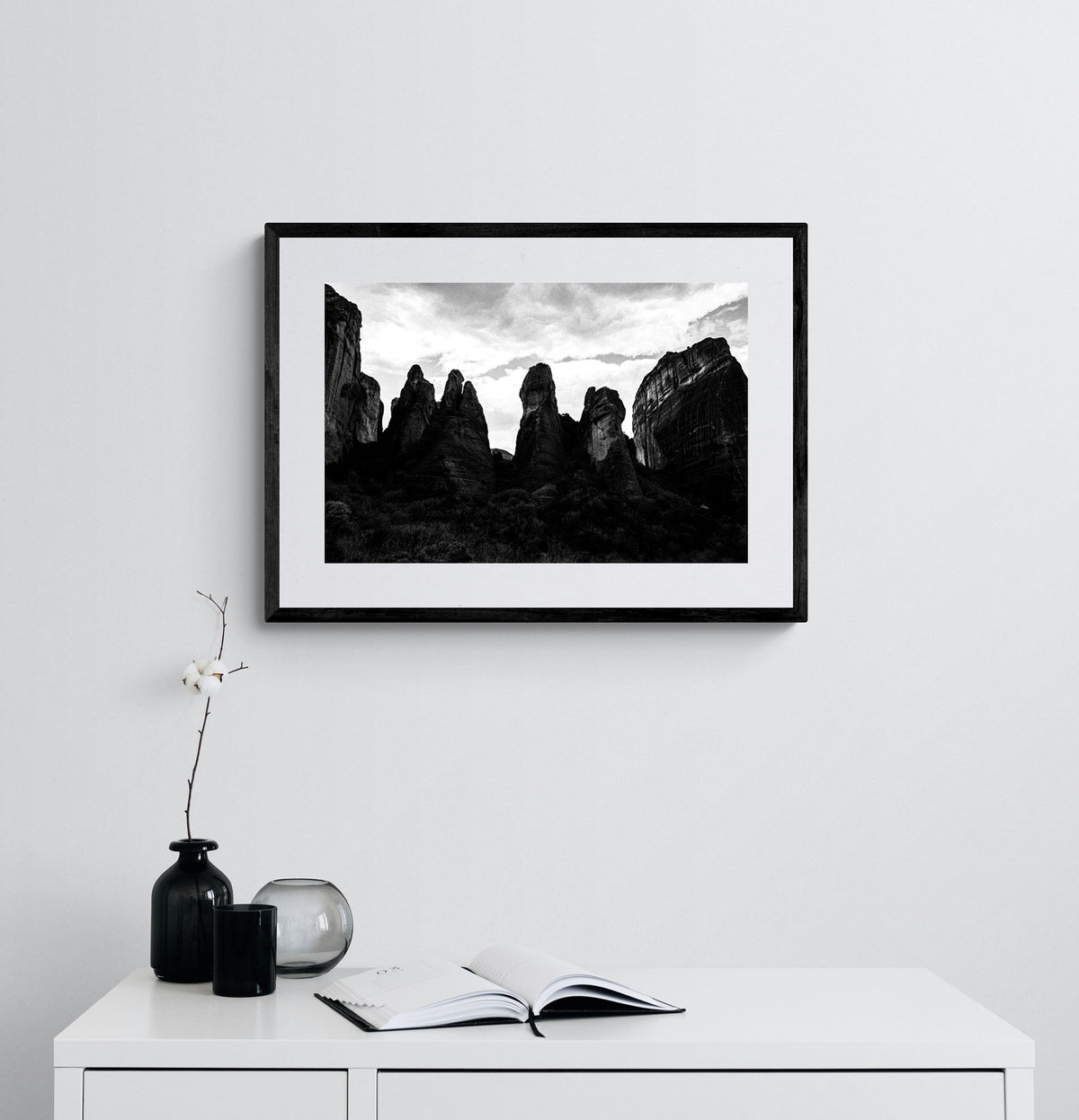 Meteora pillar formations. Black-and-white photography print by George Tatakis, from the project Chorōs. Framed on a white wall