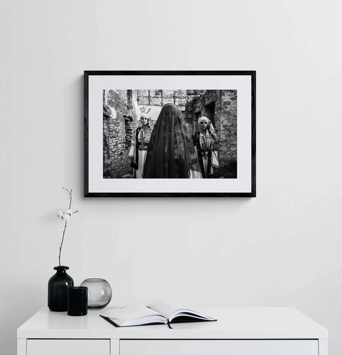 Three women in traditional attire standing in stone-walled ruins. Kyparissia, Peloponnese, Greece. Black and white photography framed on a wall by George Tatakis.